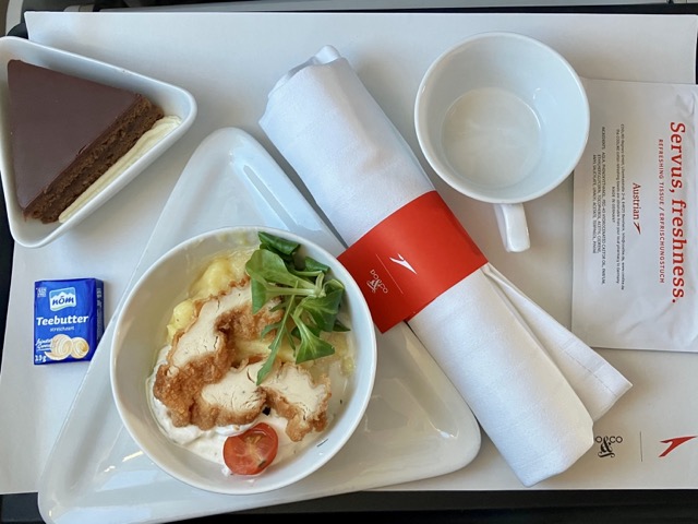 オーストリア航空ビジネスクラス（短距離路線）で提供された機内食。メインはBackhendlsalat（フライドチキンサラダ）、デザートはザッハトルテ、そしてバター（Teebutter）とカトラリー