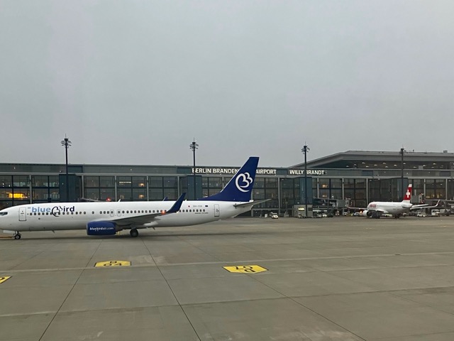 BERのエプロン（駐機場）から見たターミナルビル。外壁には「BERLIN BRANDENBURG AIRPORT WILLY BRANDT」の文字が見える。手前にはブルーバード航空機