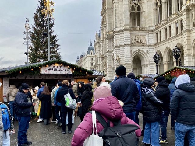 ウィーンのクリスマスマーケットでソーセージの屋台にずらりと行列している人々
