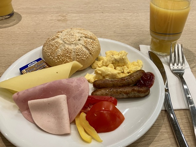 カイザーゼンメルやハム、チーズ、ソーセージ、卵料理、野菜を盛り付けた朝食プレート
