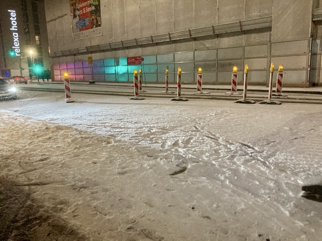 夜のミュンヘン。雪に覆われたホテルアダージョの前の街路と工事現場。relexa hotelの看板も見える