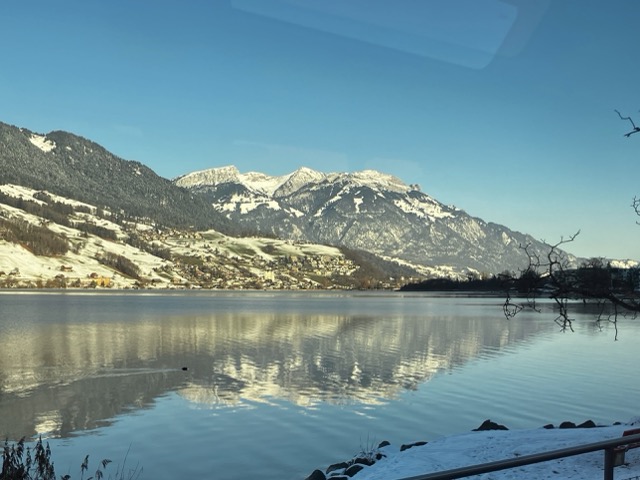 パノラマ列車の車窓から見える湖と雪をかぶった山々