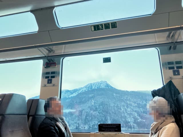 天井近くまで大きな窓が広がるスイスのパノラマ列車の車内と窓から見える雪山