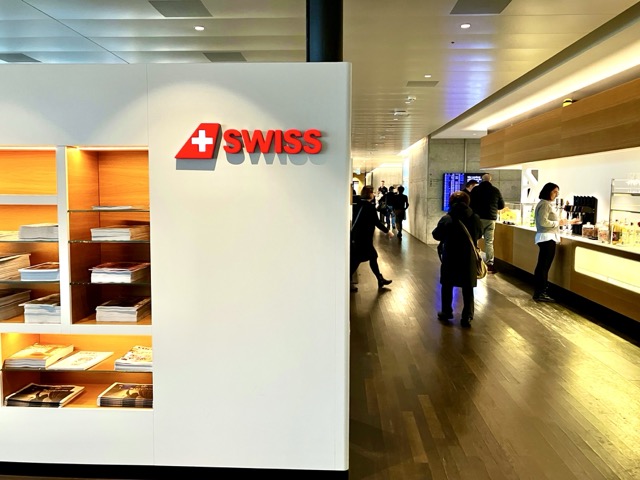 チューリッヒ空港SWISSビジネスラウンジのエントランスにある真っ赤な「+ SWISS」のブランドロゴマーク