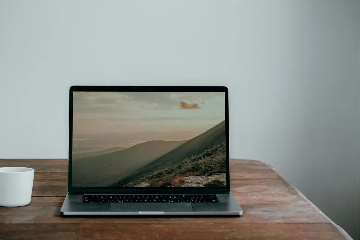デスクの上にMac Bookとコーヒーが並んでいる。