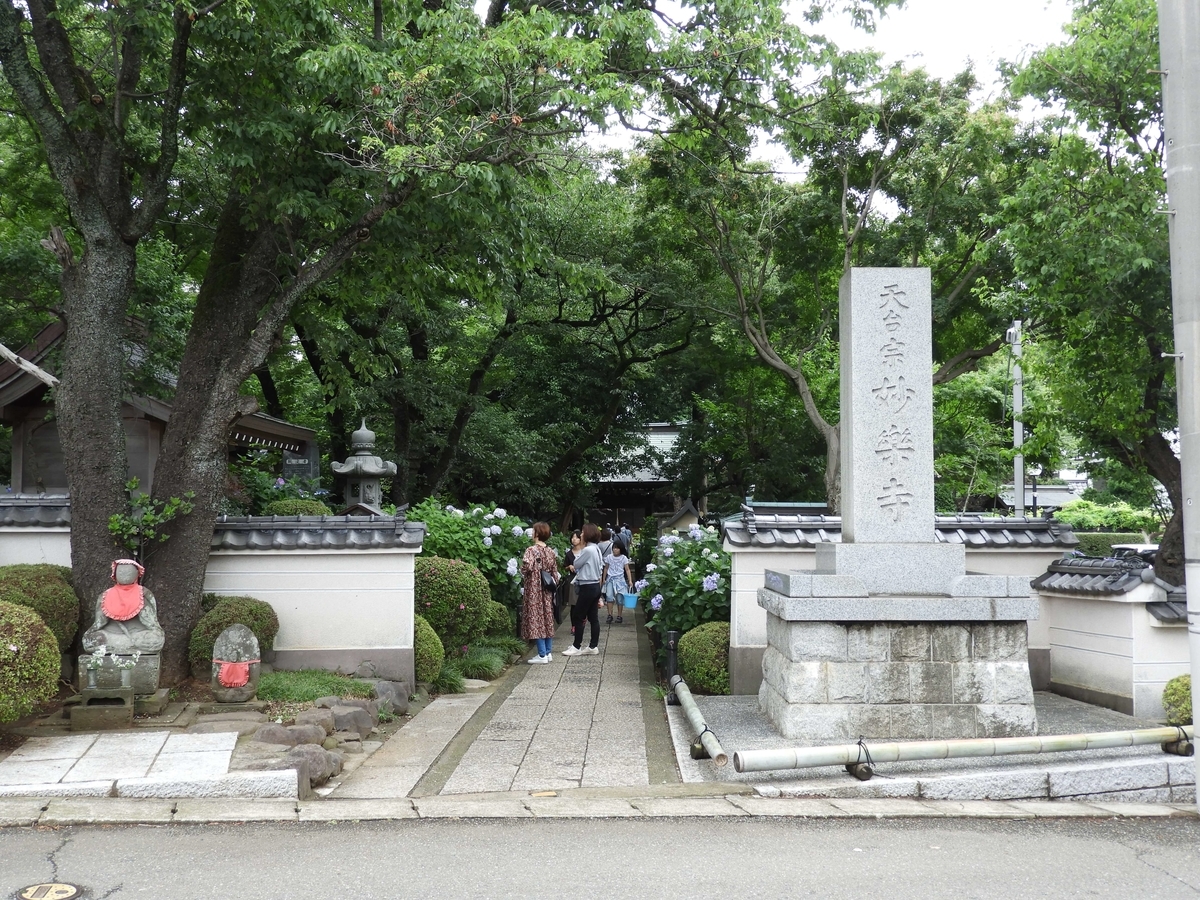 妙楽寺の寺号標とお参りしている人々