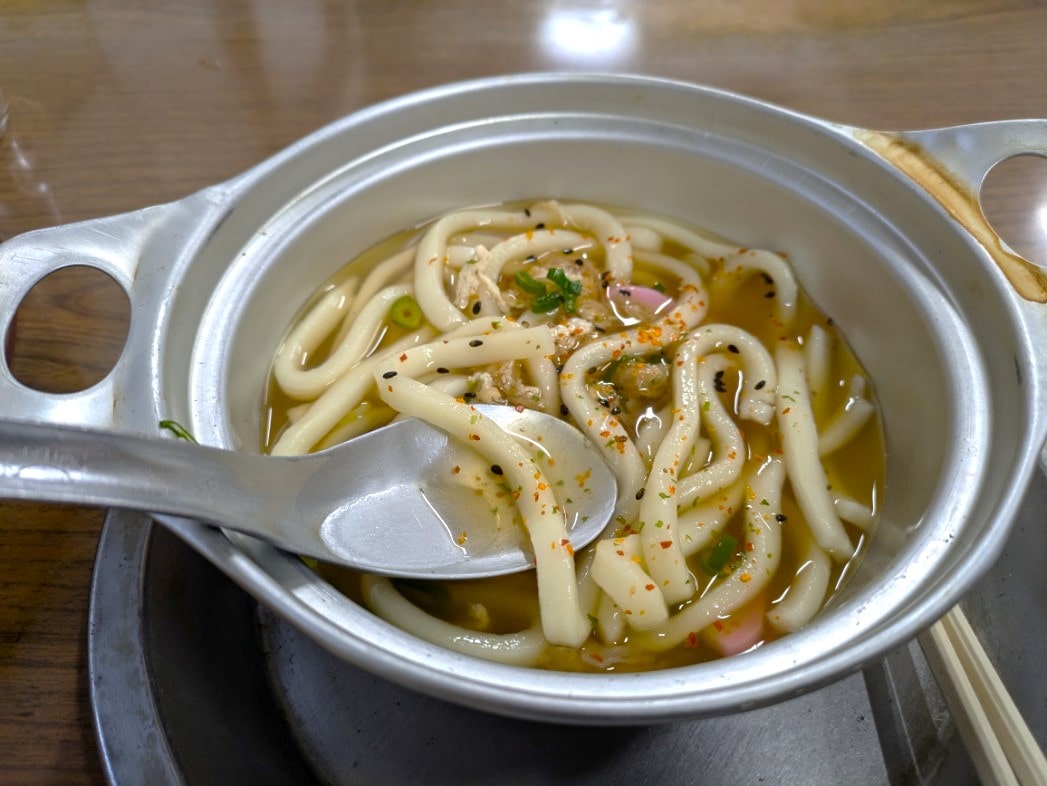 七味唐辛子をかけた鍋焼きうどん
