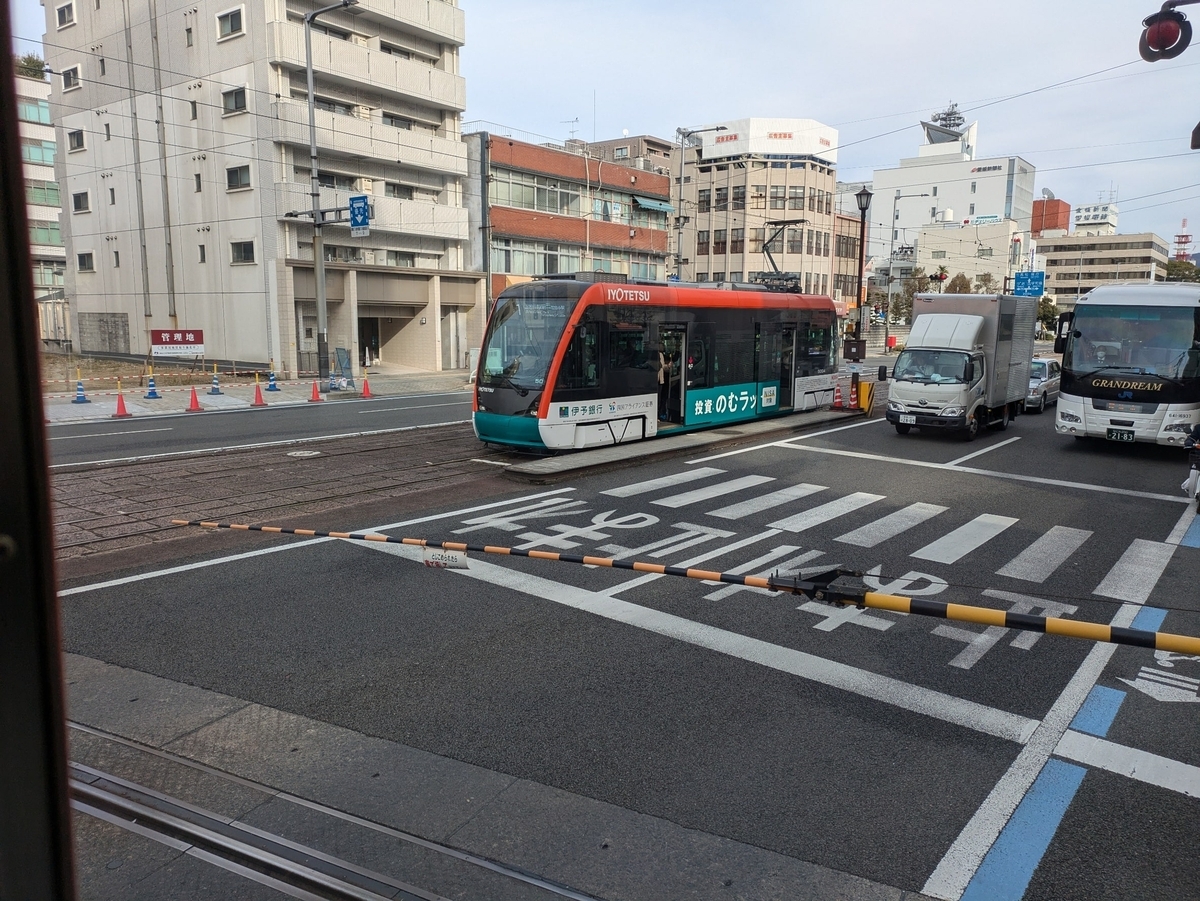 踏切で電車の通過を待つ路面電車