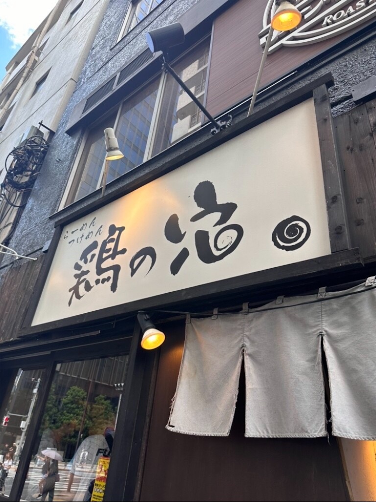池袋の有名ラーメン店の店内風景、カウンター席に座る客、大きな丼に盛られた濃厚な鶏白湯ラーメン、湯気が立ち上る温かそうな雰囲気、写実的なイラスト