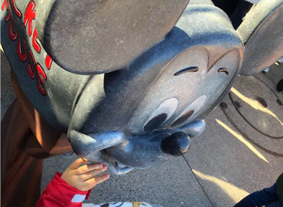 ディズニーランドにあるミッキーのポストを触る子ども