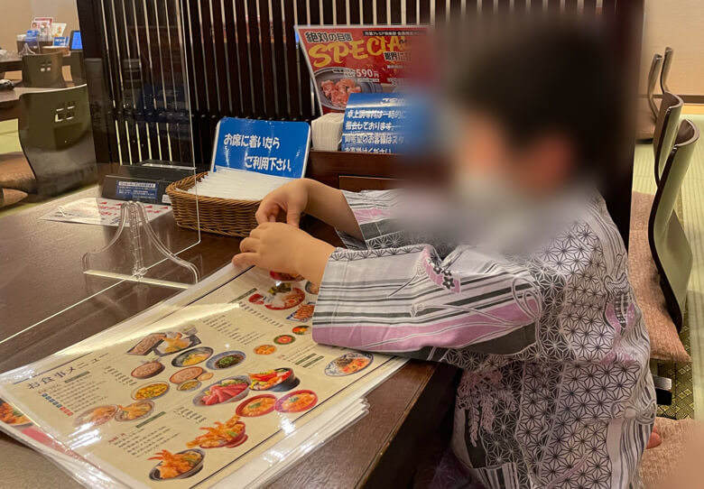 万葉の湯の町田の食事処で座っている子ども