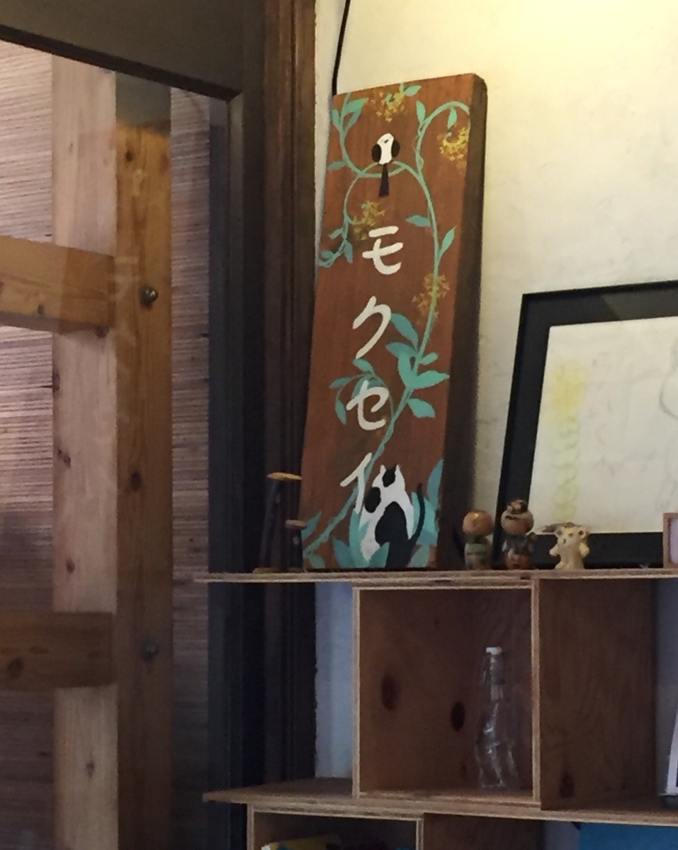 棚の上に飾られた「モクセイ」と書かれた小鳥と猫の絵の看板らしき板