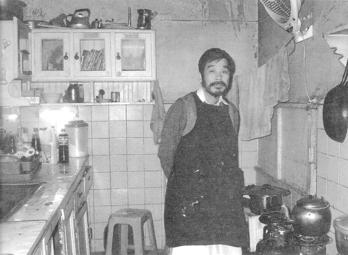 荒野さんと当時のキッチン。ガスボンベの上部がコンロになっている。(書籍222ページ)