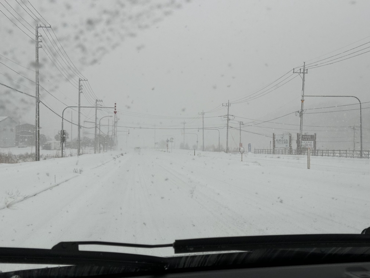 車の助手席からの写真。雪道。ホワイトアウト。路面は圧雪路。