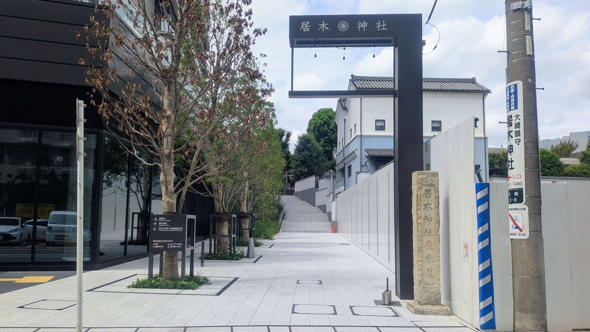 大崎ステーションタワーと工事現場の白い仮囲いに挟まれて奥に向かってのぼって行く居木神社の真新しい参道