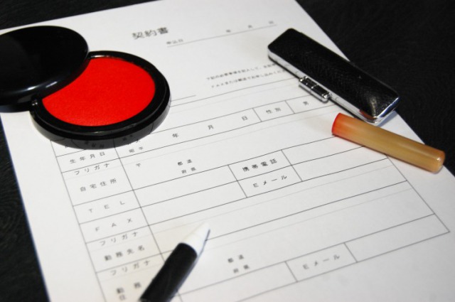 契約書の上の印鑑と朱肉とボールペン 契約書の上の印鑑と朱肉とボールペン