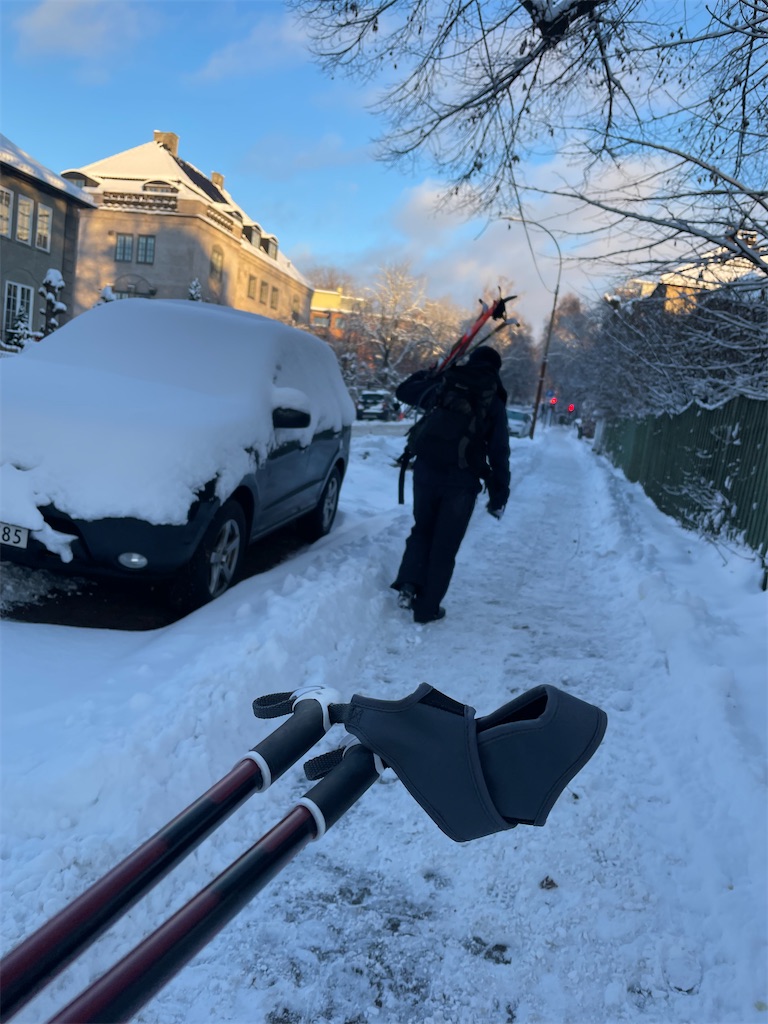 雪の積もる住宅街をスキーを持って歩く