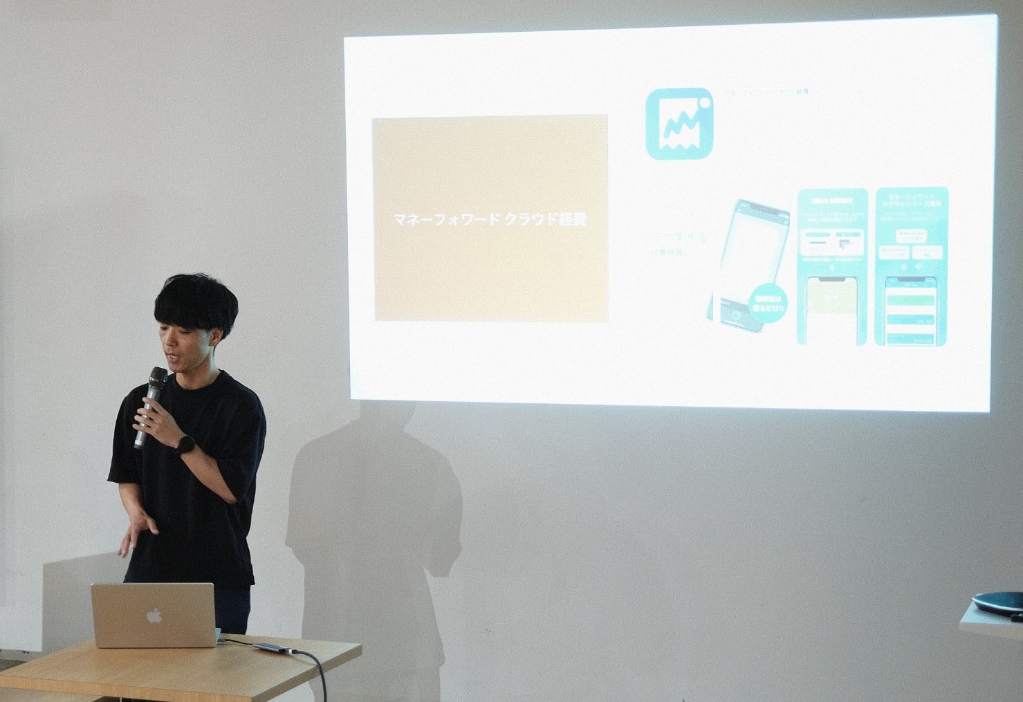 shinoが登壇している写真。マイクを片手に、iOSアプリの信頼性を向上させる取り組みについて話している。