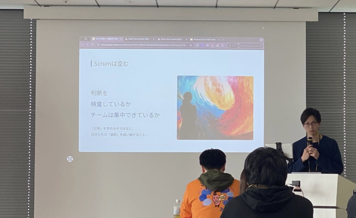 登壇者の蘆原さんがマイクを持って喋っている写真。