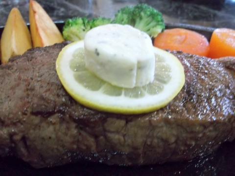 つくばエクスプレス六町駅を最寄駅とする東京都足立区東保木間1丁目にあるステーキとハンバーグの花もようのニュージーランド産サーロインステーキ300gステーキの上にレモンと香草バター