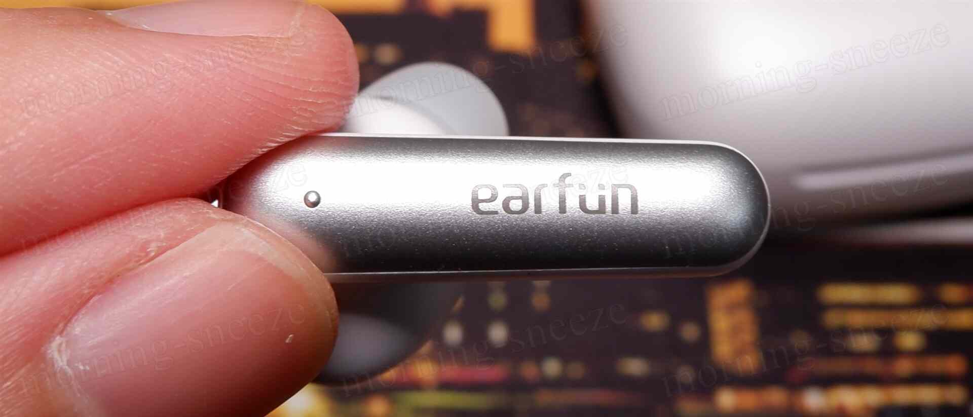 ワイヤレスイヤホンが手で持たれています。イヤホンの側面には「earfun」と刻まれており、近くには小さな突起があります。