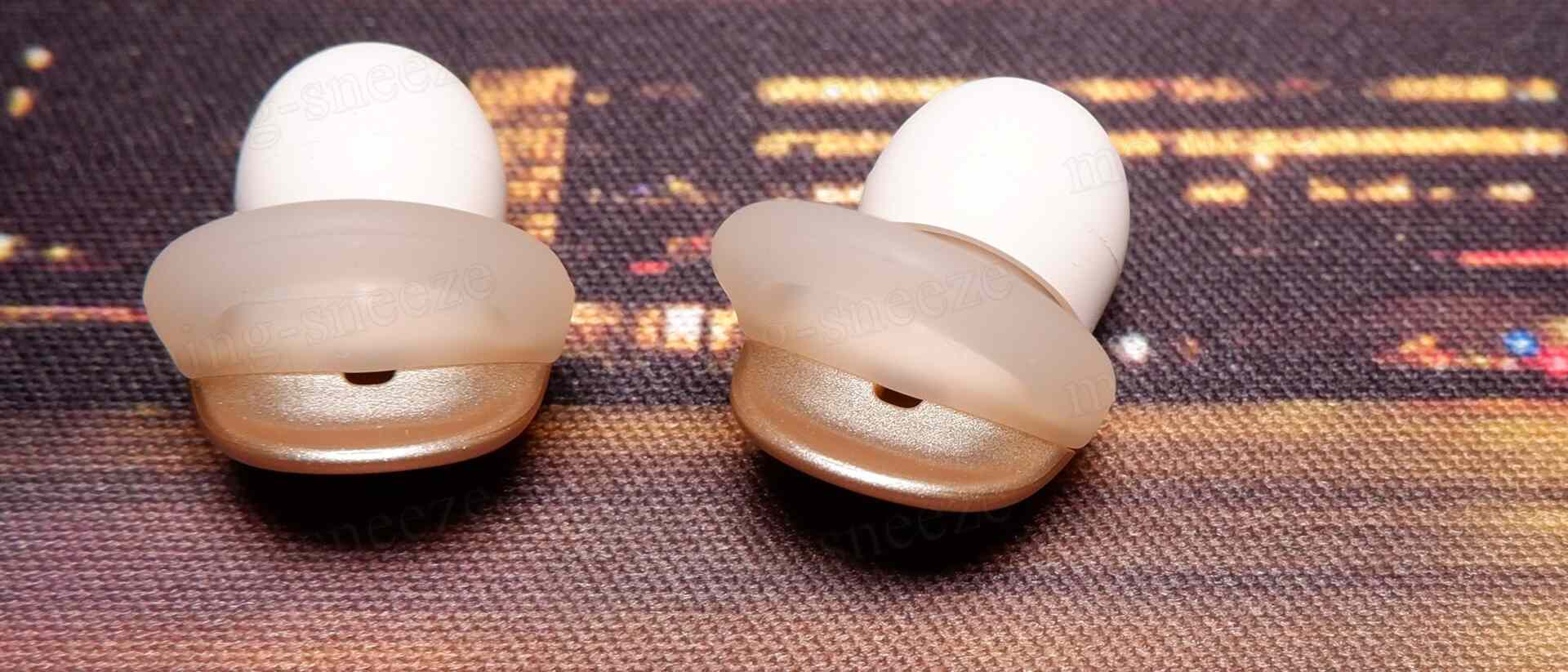 白い耳栓がふたつ、透明なシリコンの部分と金色のシェルを持っている。