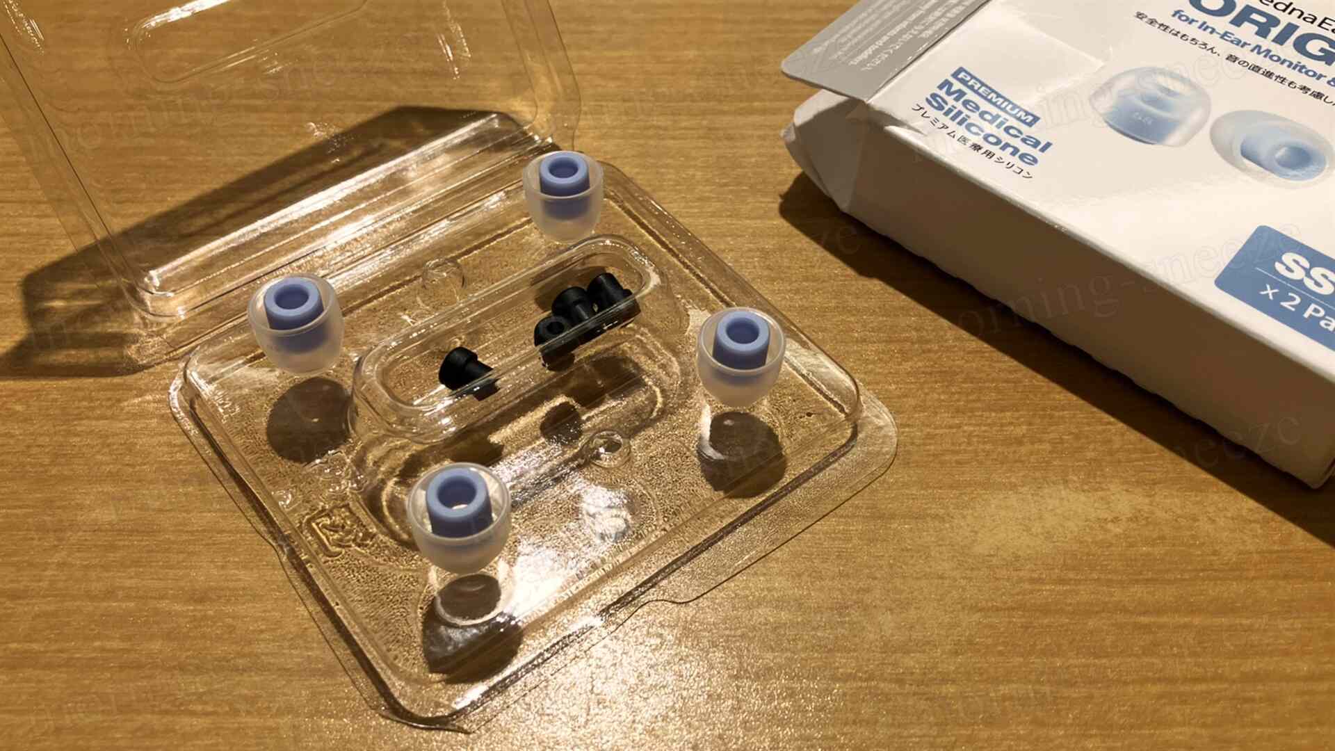 透明なパッケージの中に入ったいくつかの耳栓が並んでいる。シリコン製の耳栓と黒いアダプターが含まれており、隣にはそのパッケージが見える。