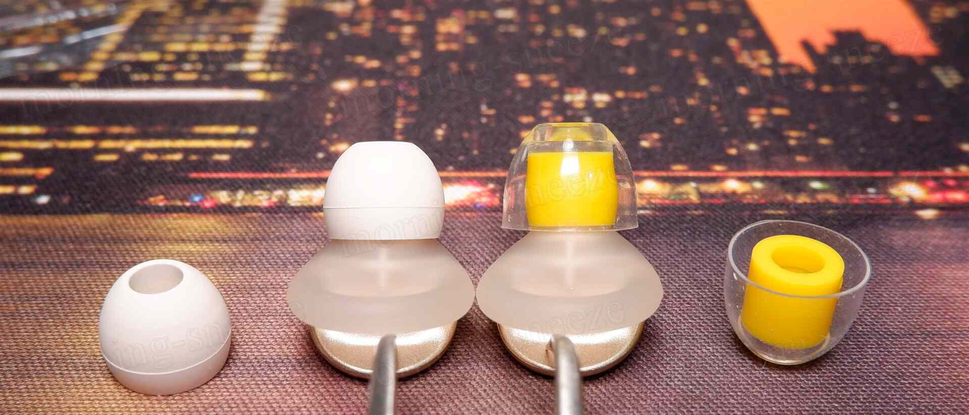 イヤホンのイヤーチップが並んでいる画像。左側には白いシリコン製のイヤーチップがあり、真ん中には透明なケースに収められた黄色いイヤーチップと、その下に白いイヤーチップがある。右側にも黄色いイヤーチップが入った透明なケースが見える。
