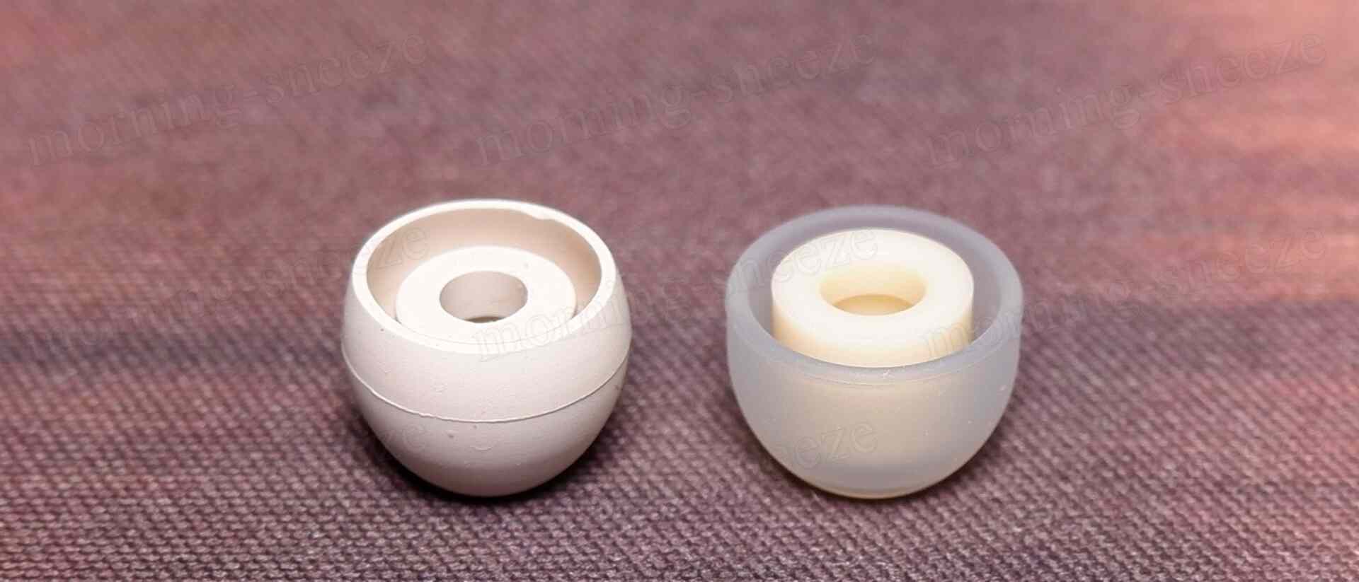 上記を横から見た図。白いイヤーチップが二つ並んでいる。左側はマットな質感の白いもので、右側は半透明のクリーム色の質感を持つ。