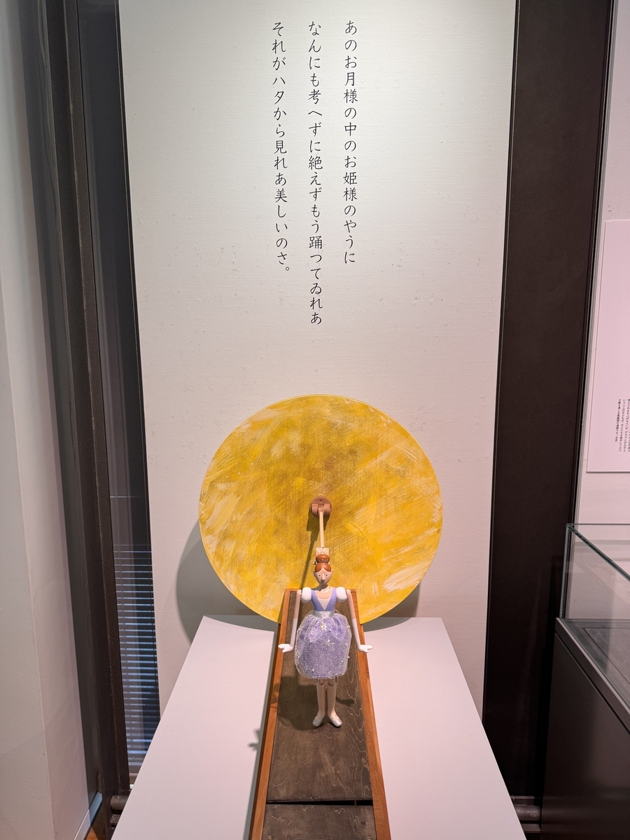 瀟洒な服を着た赤髪の女性の人形が月をバックに立っており、起動すると踊り出します。背景には「あのお月様の中のお姫様のやうに/何にも考へずに絶えずもう踊つてゐれあ/それがハタから見れあ美しいのさ。」中也の詩からの引用が書かれています。