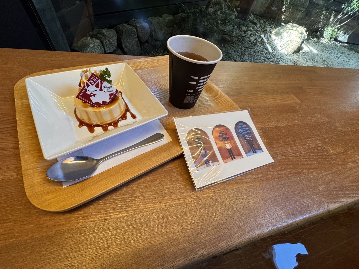足湯とプリンと紅茶。手前には「生ひ立ちの歌」のオートマタのポストカード。奥には日が差す中庭。