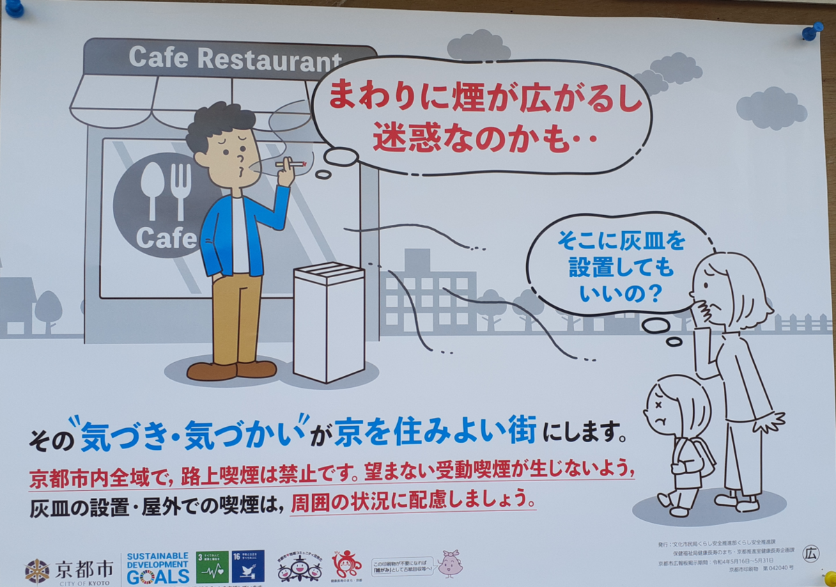 京都市の啓発ポスター。飲食店前で男性が灰皿のそばで喫煙し、煙が周囲に広がっている。通行中の女性と子どもが煙を嫌がっており、「そこに灰皿を設置してもいいの?」「まわりに煙が広がるし迷惑なのかも・・」と書かれている。