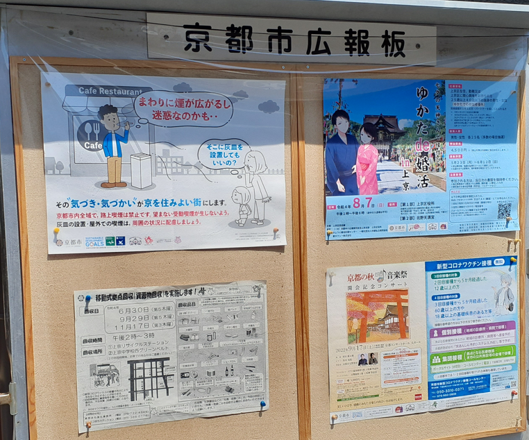 京都市広報板の全体写真。左上に令和4年度の路上喫煙・受動喫煙防止啓発ポスターが掲示され、右側や下部にはイベント案内や市政情報のポスターが並んでいる。