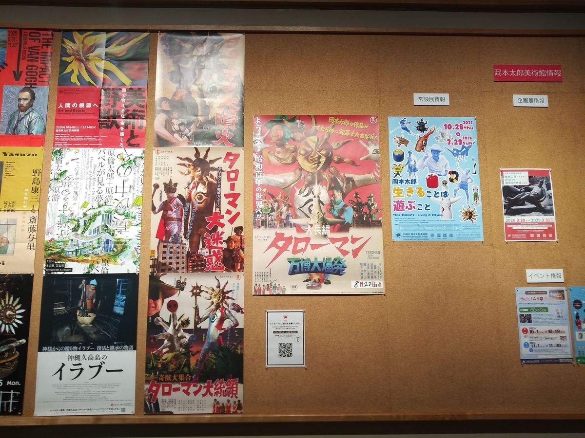 川崎市岡本太郎美術館「タローマン大万博川崎パビリオン」岡本太郎美術館情報の壁　常設展示のポスターの横に劇場版の「大長編　タローマン　万博大爆発」のポスターが！