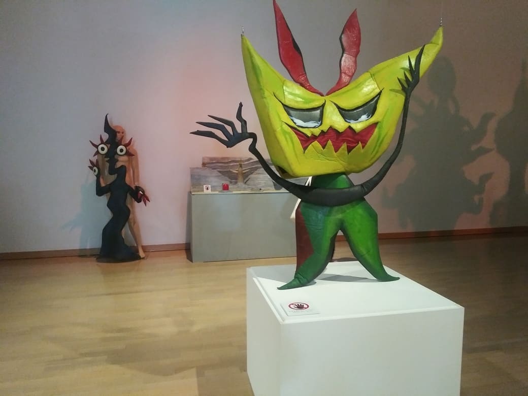 岡本太郎美術館　企画展示室「タローマン大万博川崎パビリオン」べらぼうな奇獣駄々っ子の人形、その後ろにみつめあう愛の人形と地底王国模型