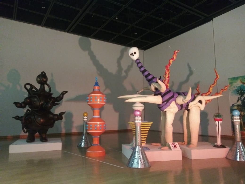 岡本太郎美術館　企画展示室「タローマン大万博川崎パビリオン古代奇獣縄文人と神話奇獣明日の神話が並んで展示されている、周囲には昭和100年の街並みを再現した建物が置かれている」