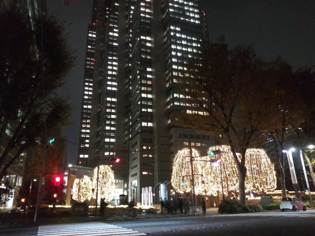 西新宿3_新宿パークタワーのウインターイルミネーション2025　目の前の交差点からライトアップされた木々と背後にパークタワーー