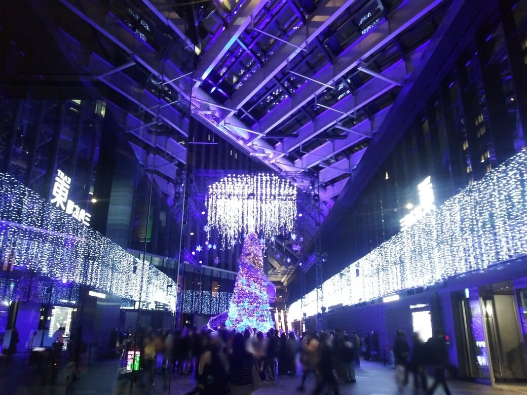 西新宿2_新宿住友ビルのクリスマスイルミネーション_『snow flow』　色のバリエーションその1：青と水色に輝くツリーとその横の螺旋階段を引きで見る