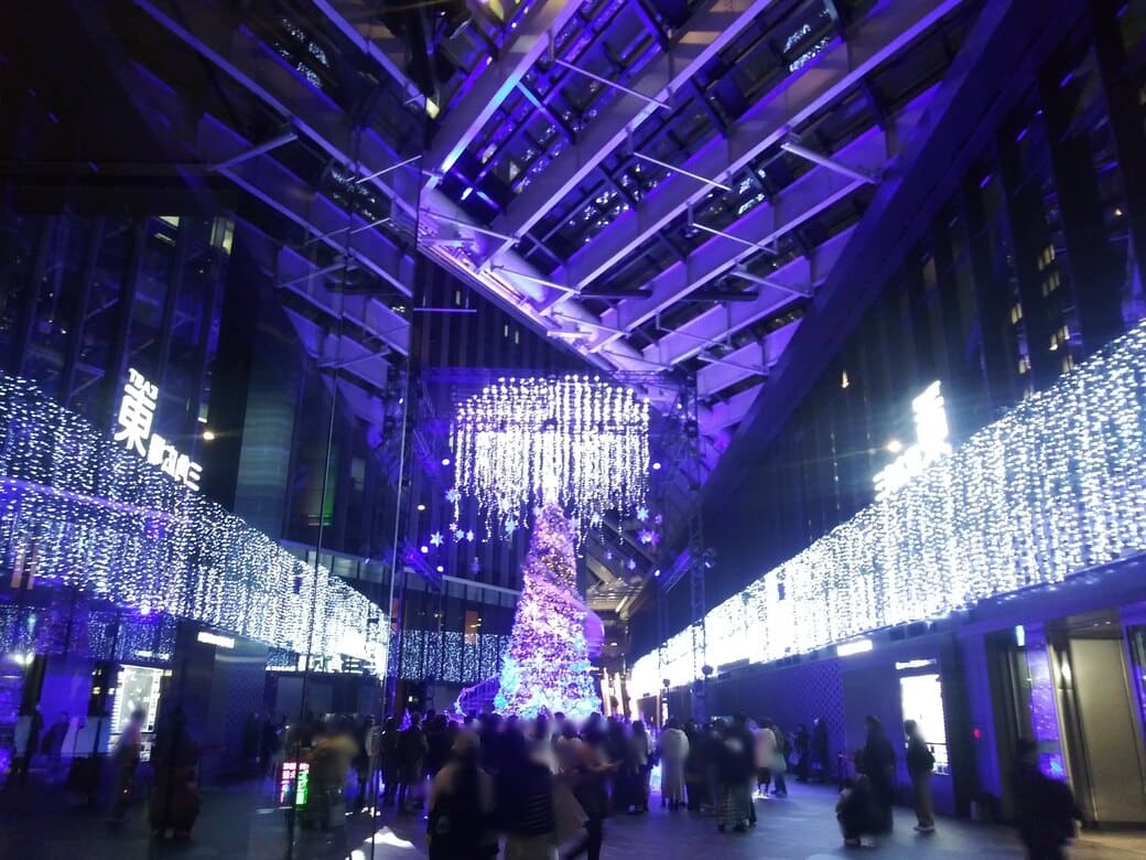 西新宿2_新宿住友ビルのクリスマスイルミネーション_『snow flow』　色のバリエーションその1：青と紫色に輝くツリーとその横の螺旋階段を引きで見る