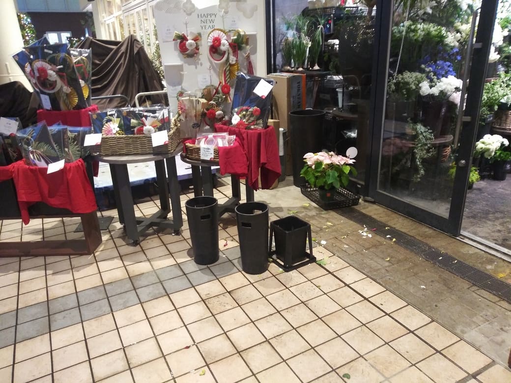 たまプラーザのクリスマスイルミネーション2025年_GATE PLAZA_ステーションコート_駅前　青山フラワーマーケットでは正月用の花卉とクリスマス用のポインセチアが同居していてこの季節らしい雰囲気であった