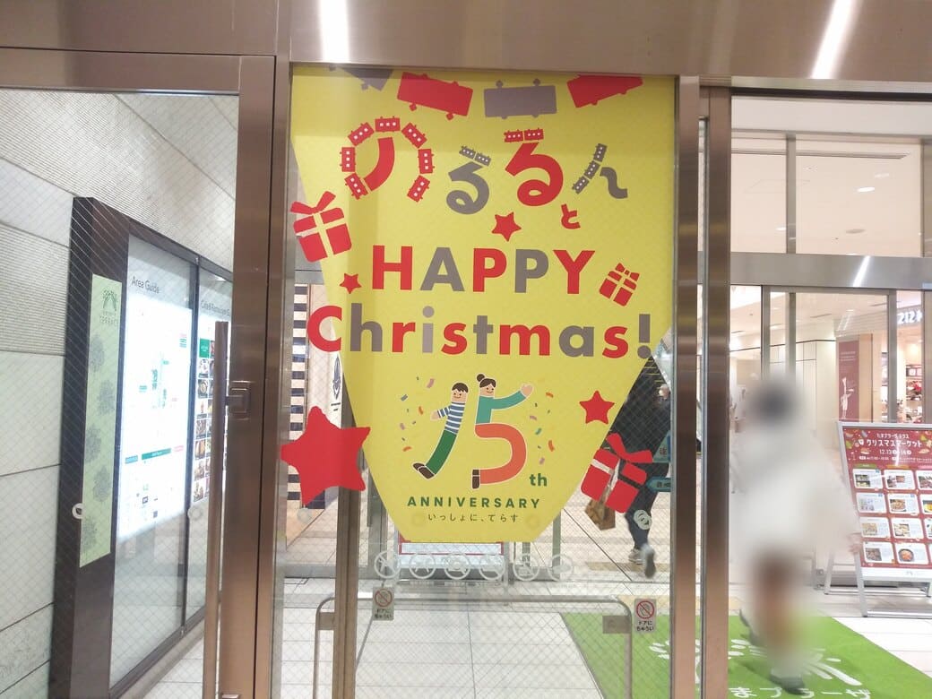 たまプラーザのクリスマスイルミネーション2025年_GATE PLAZA_フェスティバルコート1FモールB口ガラス扉横のガラス壁にたまプラ5周年のマークが貼られてあった