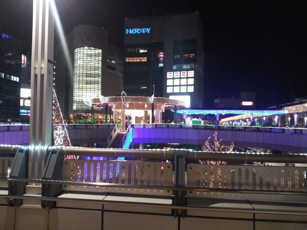 2025年第26回 溝口駅前 キラリデッキイルミネーション　キラリデッキの東急ストア側から見た円筒広場のライトアップ、ノクティ1，2を背景に