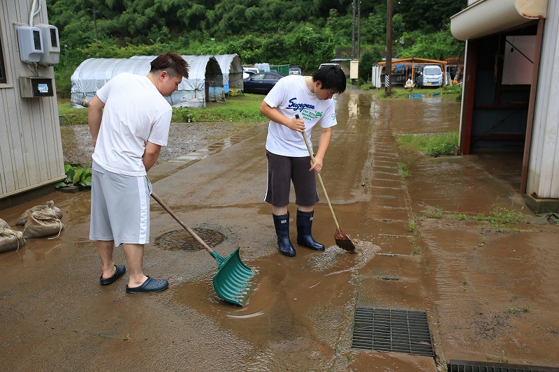 道端の泥を流す住民＝８日６時１２分関市神野・下日立地区で