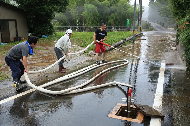 消火栓から水を出し、ホースで泥を流す住民＝８日６時１３分関市神野・下日立地区で