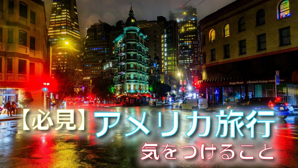 夜のサンフランシスコの街角。雨に濡れた路面に街灯や信号の光が反射し歴史的なフラットアイアンビルが建つ風景