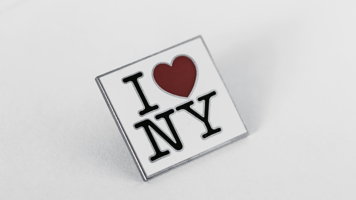 地に赤色のハートマークと黒い文字で描かれた「I LOVE NY」の正方形のピンバッジ