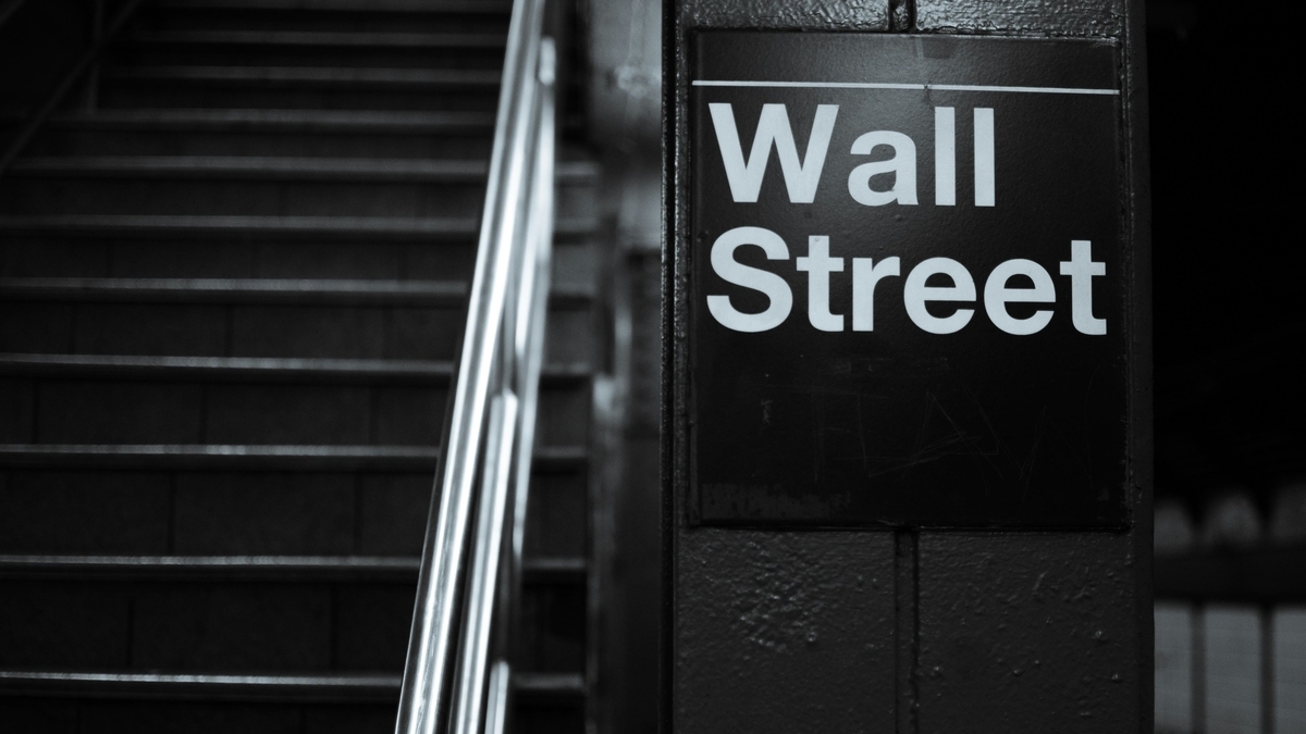地下鉄の階段横に設置された、黒い背景に白文字でWall Streetと書かれた駅名標