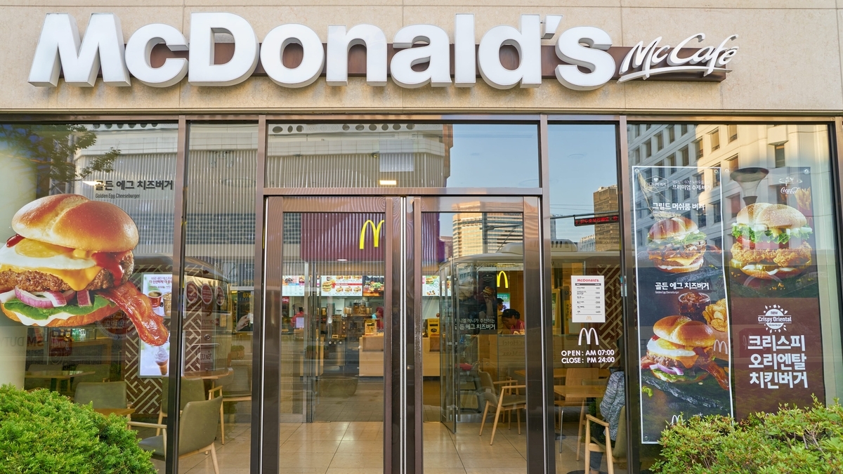 マクドナルドとマックカフェの看板が掲げられた店舗の外観。ガラス扉には「GOLDEN EGG CHEESEBURGER」などのメニューポスターが貼られている