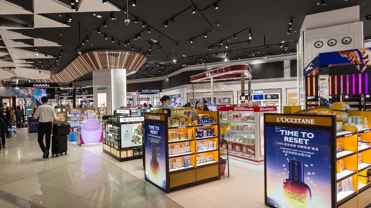 「L'OCCITANE（ロクシタン）」などの高級化粧品ブランドが並ぶ空港内の免税店。黒を基調とした天井に多くのスポットライトが設置され、明るく照らされたディスプレイ棚に色とりどりの商品が陳列されています