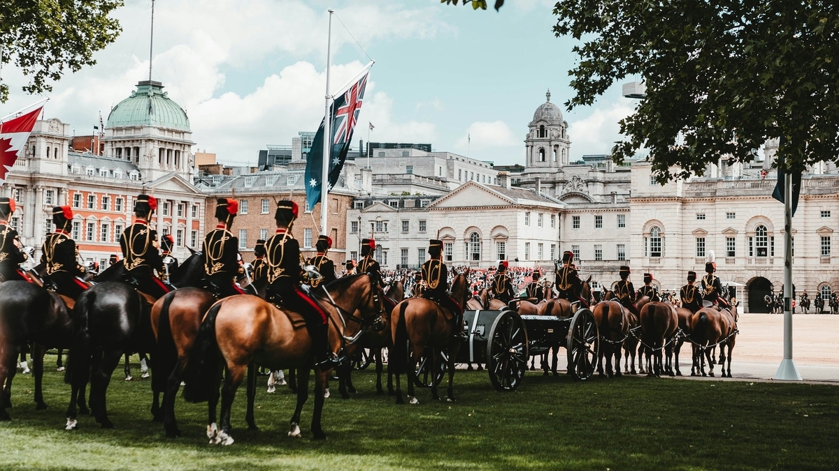 ロンドンのホース・ガーズ・パレードにて、伝統的な礼装を纏った騎兵隊が馬に乗り、大砲を引いて整列する荘厳な式典の様子です